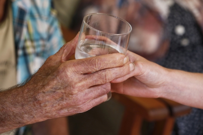 A care nurse gives a glass of water to an elderly woman as she sits in the living room of a retirement home in Bordeaux, southwestern France, June 30, 2015. An unusual heat wave sweeps France this week with temperatures which could reach 40 degrees Celsius, records are expected in southwestern regions of France.