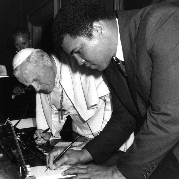 Pope John Paul II and former Muhammad Ali sign autographs for each other at the end of their meeting at the Vatican in 1982.