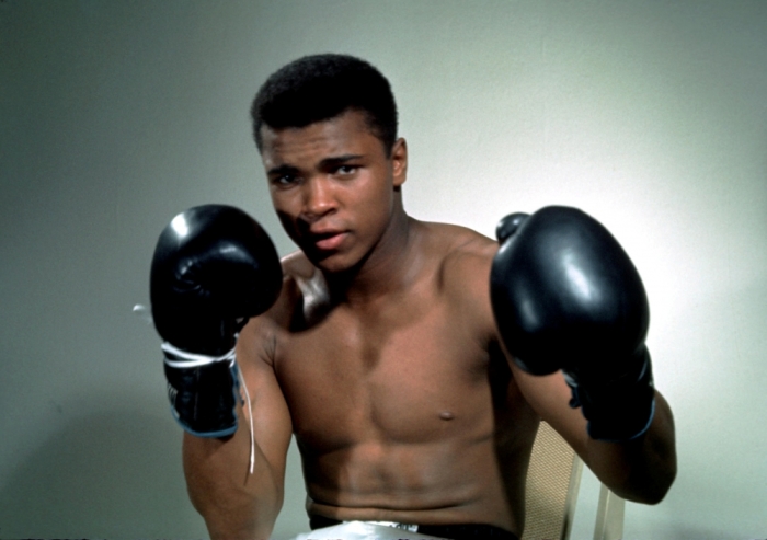 Muhammad Ali posing with his boxing gloves.