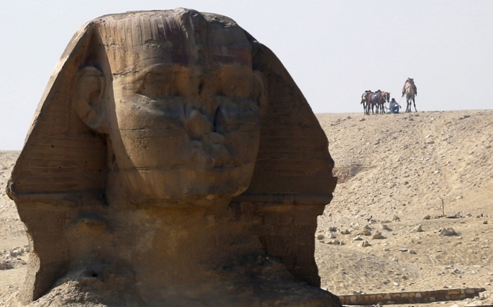 An employee waits with his camel for tourists near the Sphinx at the Giza Pyramids on the outskirts of Cairo, Egypt, March 2, 2016.