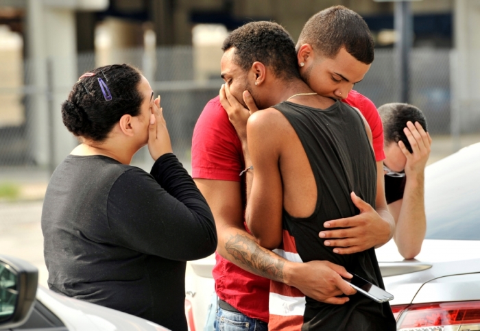 Friends and family members embrace outside the Orlando Police Headquarters during the investigation of a shooting at the Pulse night club, where as many as 20 people have been injured after a gunman opened fire, in Orlando, Florida, U.S June 12, 2016.
