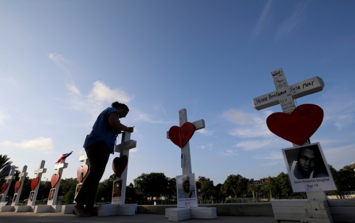 A woman writes a message on a cross in honor of those who were killed at the Pulse gay nightclub in Orlando, Florida, U.S. June 17, 2016.