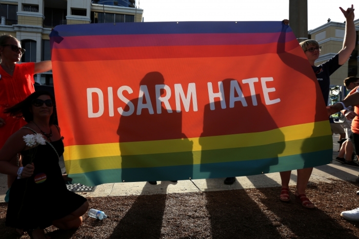 Supporters hold up a 'Disarm Hate' sign to block protesters during a vigil for the Pulse night club victims following last weeks shooting in Orlando, Florida, U.S., June 19, 2016.