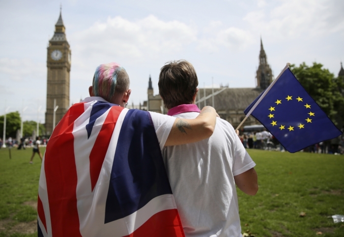 Participants with a British Union flag and an EU flag sit and look at the Big Ben clocktower after attending a pro-EU referendum event at Parliament Square in London, Britain June 19, 2016.