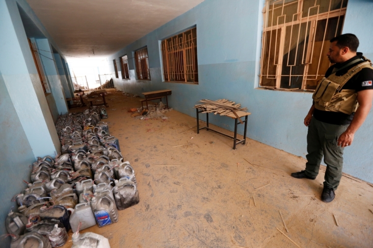 A member of the Iraqi security forces looks at explosives abandoned by Islamic State militants at a school in Falluja, Iraq, June 25, 2016.