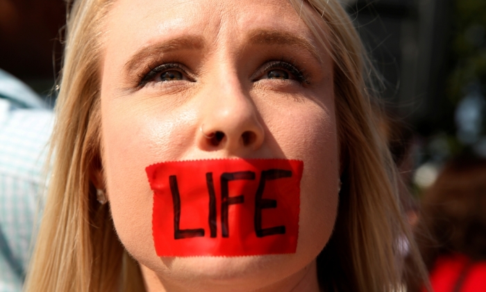 A pro-life activist with tape over her mouth demonstrates outside the U.S. Supreme Court before the court handed a victory to abortion providers, striking down a Texas law requiring abortion clinics to meet basic health and safety standards, Washington June 27, 2016.