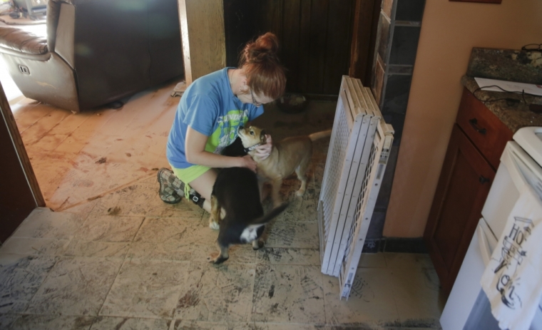 Ami Palmer, 40, is reunited with her dogs, Carlos and Rosie, as she enters her home for the first time since the flooding damage in Clendenin, West Virginia, U.S., June 26, 2016. Palmer was out of town when the flooding struck Thursday night, but her dogs were able to survive inside her home.