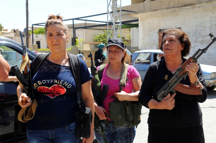 Women pose with guns in front of journalists in the Christian village of Qaa, where suicide bomb attacks took place on Monday, in the Bekaa valley, Lebanon June 28, 2016.
