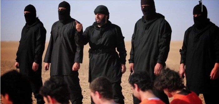 Islamic State militants stand in a line in the Syrian desert while the lead executioner speaks before the men behead five accused spies in a publicized execution video that was posted to pro-IS media outlets on June 28, 2016.