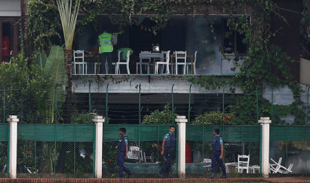 Policemen patrol outside the Holey Artisan Bakery and the O'Kitchen Restaurant as others inspect the site after gunmen attacked, in Dhaka, Bangladesh, July 3, 2016.