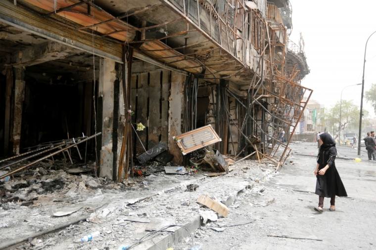 A girl walks past the site after a suicide car bomb attack at the shopping area of Karrada, a largely Shi'ite district, in Baghdad, Iraq, July 4, 2016.
