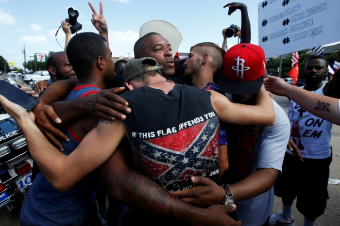 People, including a man wearing a confederate flag, hug after taking part in a prayer circle after a Black Lives Matter protest following the multiple police shootings in Dallas, Texas, U.S., July 10, 2016.