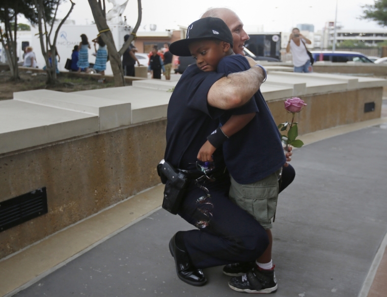 A Dallas Police officer hugs a child who came to pay respects at a makeshift memorial at Dallas Police Headquarters following the multiple police shootings in Dallas, Texas, U.S., July 9, 2016.