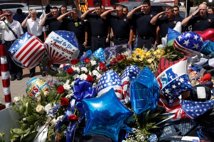 Members of the Dallas Fire Department salute after they brought a wreath of support to a makeshift memorial at police headquarters following the multiple police shootings in Dallas, Texas, July 11, 2016.