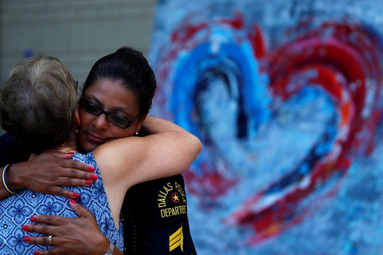 A woman hugs a Dallas police officer at a makeshift memorial at police headquarters following the multiple police shootings in Dallas, Texas, July 12 2016.