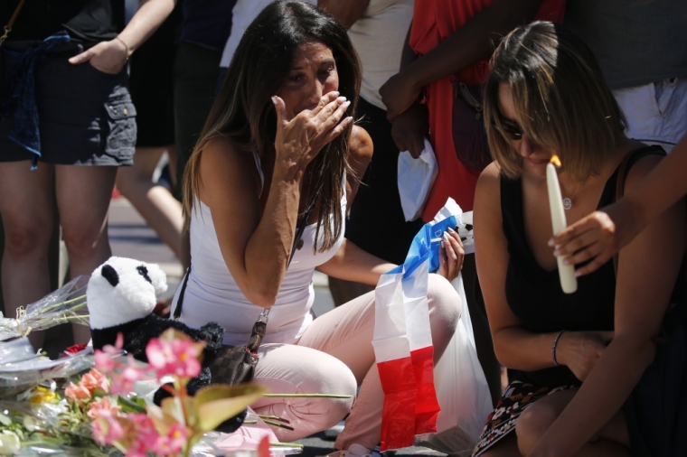 Women react near flowers placed in tribute to victims, two days after an attack by the driver of a heavy truck who ran into a crowd on Bastille Day killing scores and injuring as many on the Promenade des Anglais, in Nice, France, July 16, 2016.