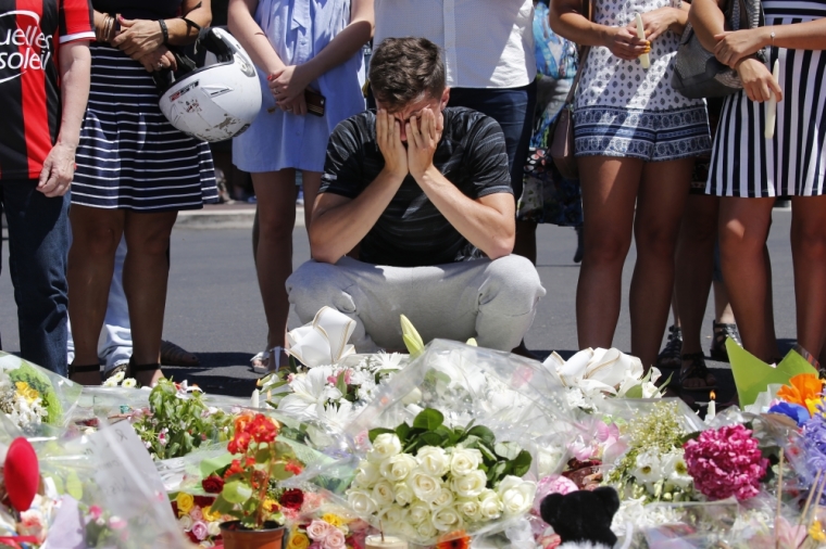 A man reacts near flowers placed in tribute to victims, two days after an attack by the driver of a heavy truck who ran into a crowd on Bastille Day killing scores and injuring as many on the Promenade des Anglais, in Nice, France, July 16, 2016.