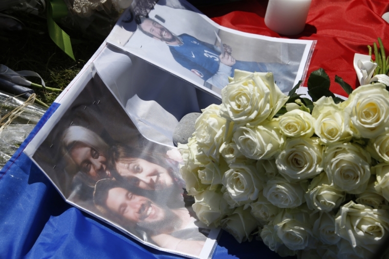 Family pictures are seen on a French flag near tributes of flowers to victims two days after an attack by the driver of a heavy truck who ran into a crowd on Bastille Day killing scores and injuring as many on the Promenade des Anglais, in Nice, France, July 16, 2016.