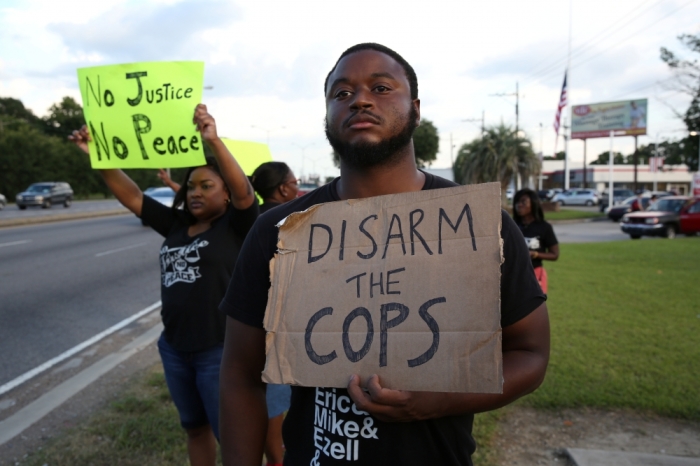 Activist Matthew Kincaid holds a sign that reads 'Disarm the cops' as he protests the killing of Alton Sterling by police officers in Baton Rouge, Louisiana, July 16, 2016.