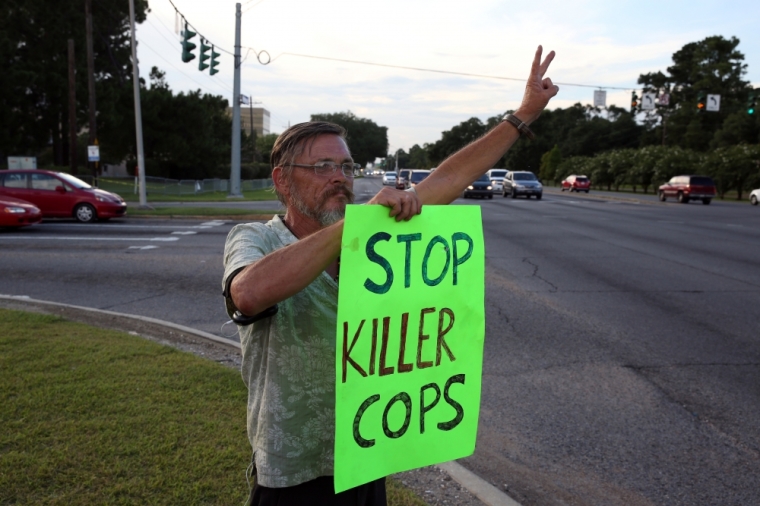 A man holds a sign reading 'Stop killer cops' as he protests the killing of Alton Sterling by police officers in Baton Rouge, Louisiana, U.S. July 16, 2016.