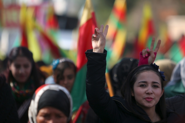 Kurdish people carry flags and flash victory signs as they take part in a protest in the city of al-Derbasiyah, on the Syrian-Turkish border, against what the protesters said were the operations launched in Turkey by government security forces against the Kurds, February 9, 2016.