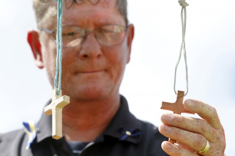 Bob Ossler, a chaplain for the Police and Fire Department of Millville, New Jersey, holds a cross at a makeshift memorial for three police officers who were shot and killed in Baton Rouge, Louisiana, July 18, 2016.