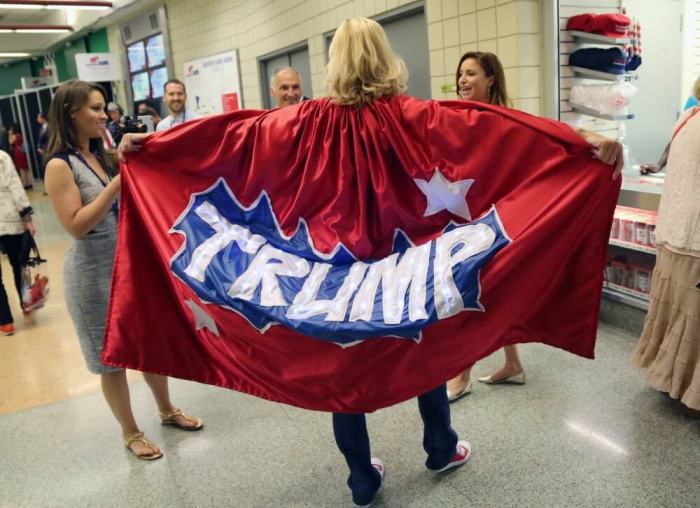 A man wearing a Trump cape talks to people during the second day.