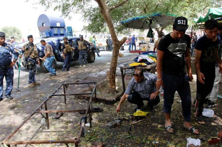 Residents and Iraqi security forces inspect the site where a suicide bomber detonated his explosive vest at the entrance to Kadhimiya, a mostly Shi'ite Muslim district in northwest Baghdad, Iraq July 24, 2016.