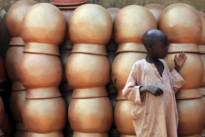 A boy stands in front of traditional handmade pots in the village of Daya near Kano, Nigeria, November 29, 2009. Daya village is well-known for their pottery in the area.