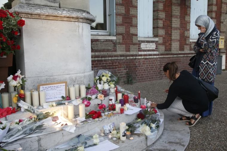 Women gather near flowers and candles at the town hall in Saint-Etienne-du-Rouvray, near Rouen in Normandy, France, to pay tribute to French priest, Father Jacques Hamel, who was killed with a knife and another hostage seriously wounded in an attack on a church that was carried out by assailants linked to Islamic State, July 26, 2016.