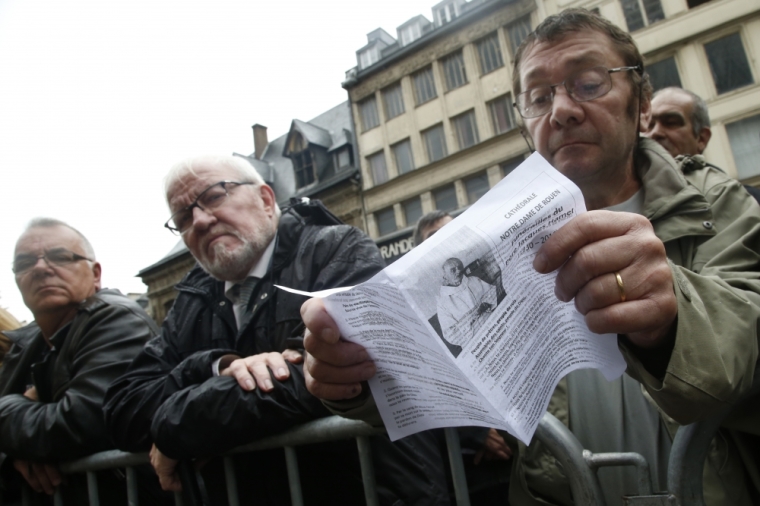 A mourner holds a leaflet with a picture of slain French parish priest Father Jacques Hamel during a funeral ceremony at the Cathedral in Rouen, France, August 2, 2016. Father Jacques Hamel was killed last week in an attack on a church at Saint-Etienne-du-Rouvray near Rouen that was carried out by assailants linked to Islamic State.