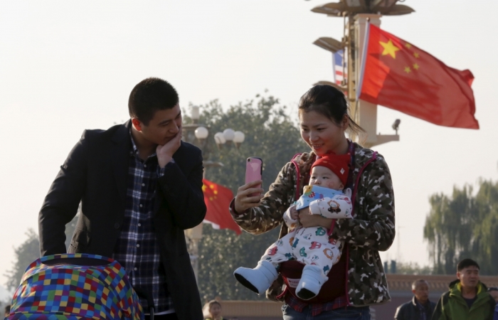A couple takes pictures with their baby on the Tiananmen Gate in Beijing, China, November 2, 2015. 