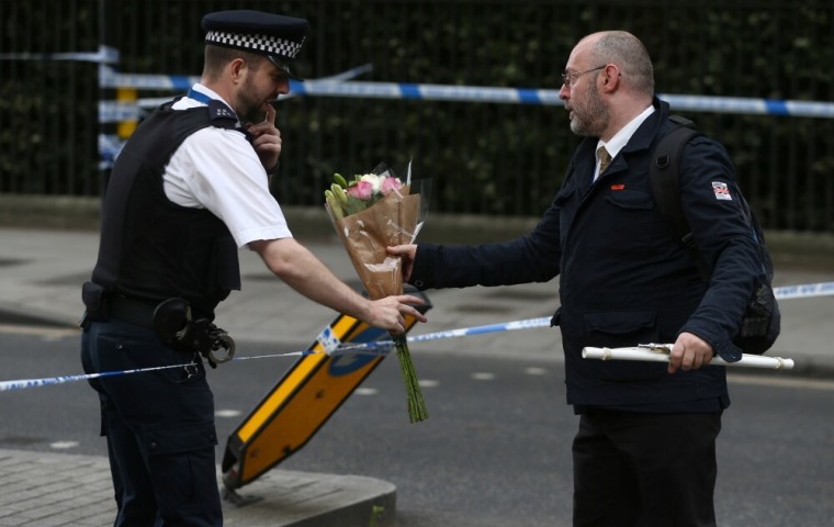 A man gives a police officer a floral tribute after a knife attack in Russell Square in London, Britain, August 4, 2016