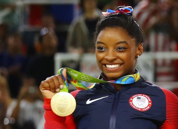 Simone Biles poses with her gold medal after the United States won gold in the women's team final in Rio de Janeiro, Brazil, Aug. 9, 2016.
