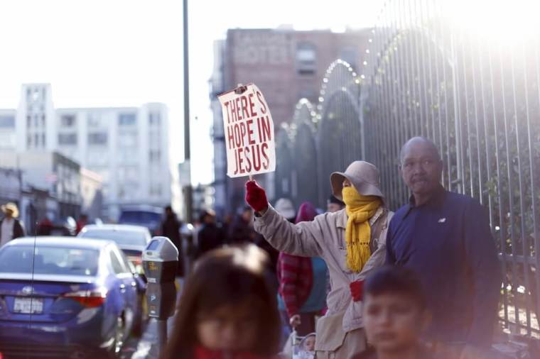 A person holds a sign while waiting in line for an early Thanksgiving meal served to the homeless at the Los Angeles Mission in Los Angeles, California, November 25, 2015.
