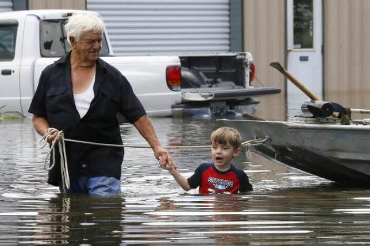Richard Rossi and his 4 year old great grandson Justice wade through water in search of higher ground after their home took in water in St. Amant, Louisiana, U.S., August 15, 2016.