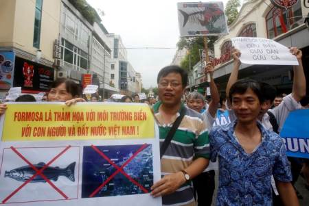 Political dissident Nguyen Xuan Dien (C) holds a sign which reads 'Formasa is disaster for Vietnam's marine environment, people and land' during a protest in Hanoi, Vietnam May 1, 2016 against a unit of Taiwan’s Formosa Plastics, a firm they blame for causing an environmental disaster and the death of large numbers of fish in central coast provinces in April. A government investigation into the fish deaths is underway but its preliminary probe found no links to Formosa's .6 billion coastal steel plant in Ha Tinh province.