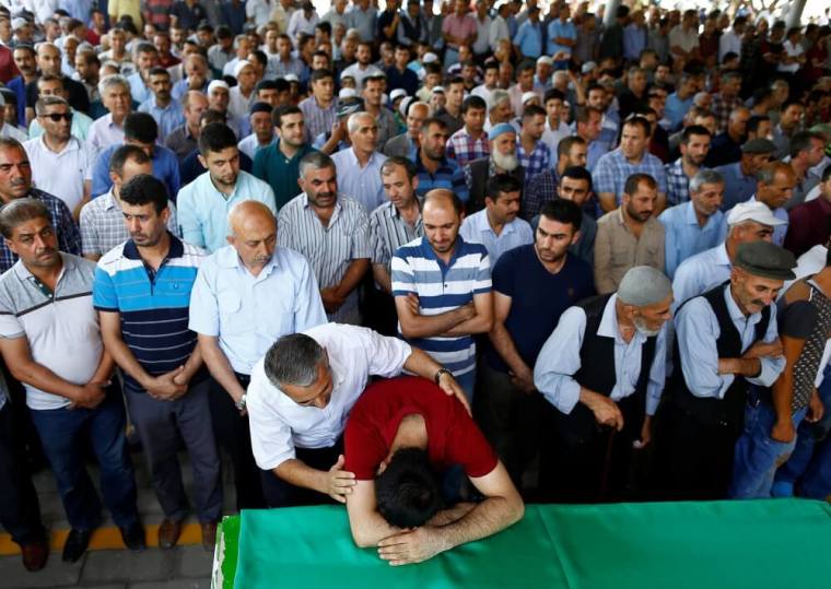 A family member of a victim of a suicide bombing at a wedding celebration mourn over a coffin during a funeral ceremony in the southern Turkish city of Gaziantep, Turkey, August 21, 2016.