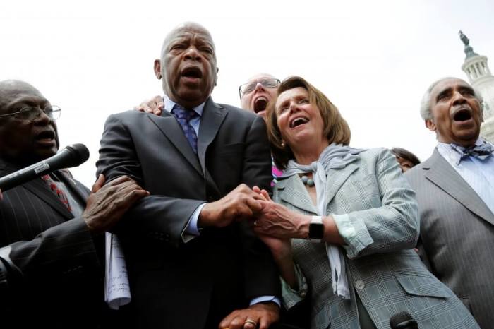 U.S. House Minority Leader Nancy Pelosi (D-CA) (2nd R) holds hands with Rep. John Lewis (D-GA) (2nd L) as they sing along with House Democrats after their sit-in over gun-control law on Capitol Hill in Washington, D.C., June 23, 2016.