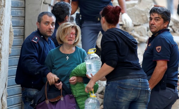 A woman (2nd L) cries after been rescued from her home following a quake in Amatrice, central Italy, August 24, 2016.
