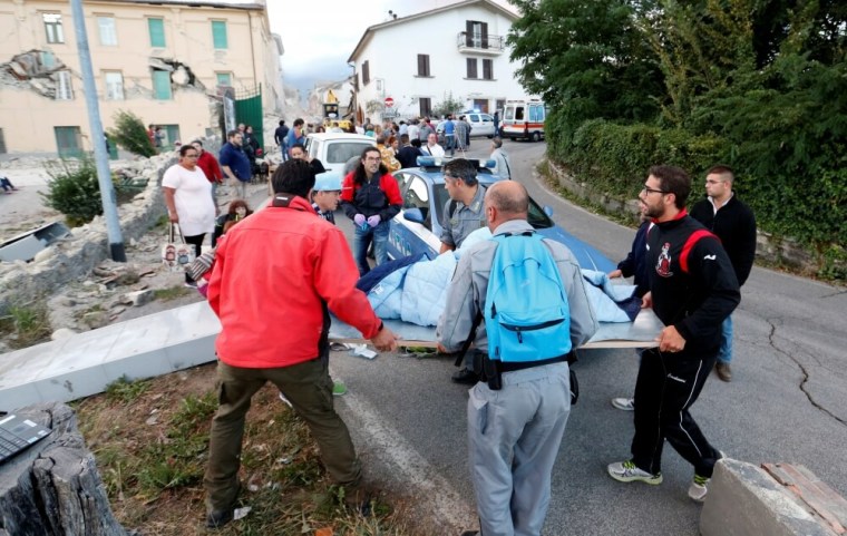 People stand along the road following a quake in Amatrice, central Italy, August 24, 2016.