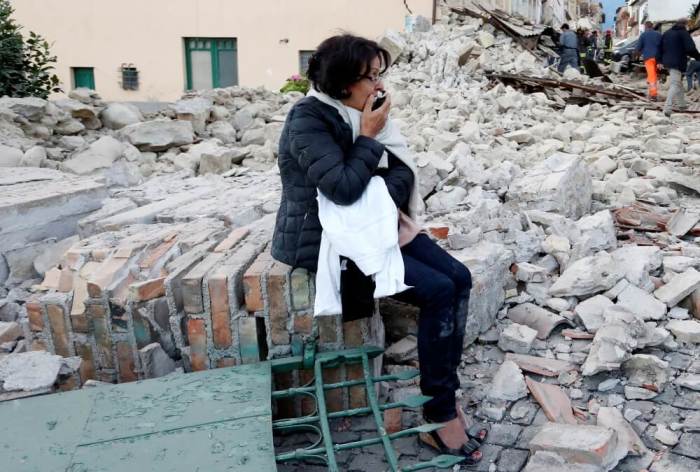 A woman sits amongst rubble following a quake in Amatrice, central Italy, August 24, 2016.