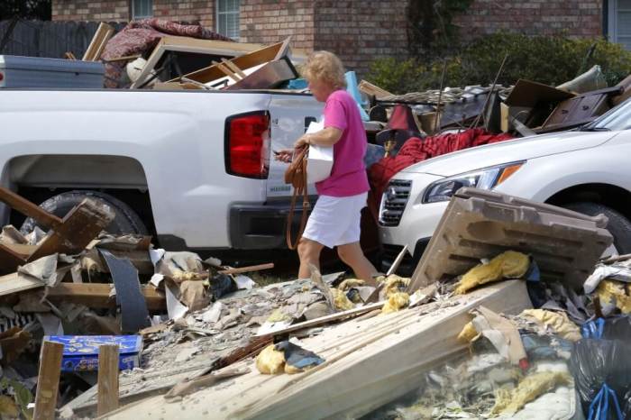 A woman walks through piles of debris in front of flood damaged homes in Prairieville, Louisiana, August 22, 2016.